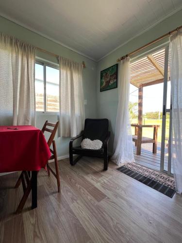 ein Wohnzimmer mit einem Tisch, einem Stuhl und einem Fenster in der Unterkunft Da Fortune 2 in Barra de Portezuelo