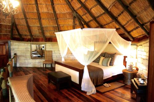 een slaapkamer met een hemelbed bij Serena Mivumo River Lodge in Mkalinzu