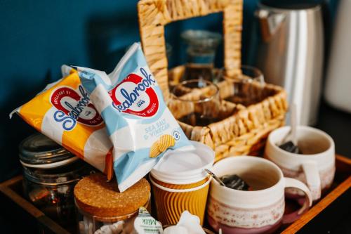 a tray with cups of coffee and a basket of food at Boutique Shrewsbury Suites in Shrewsbury