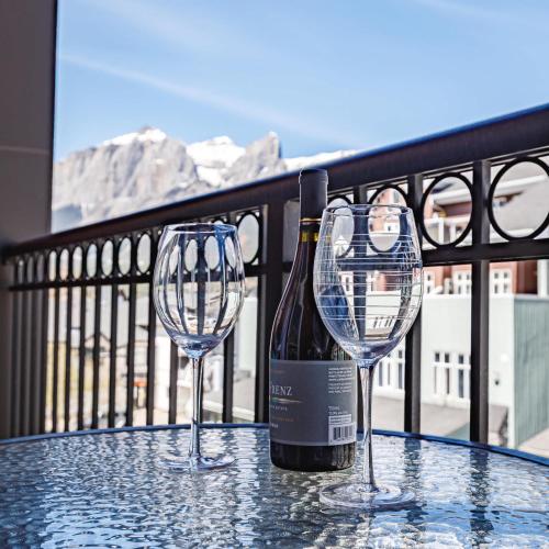 two wine glasses on a table with a bottle of wine at Westwinds - Funky Basecamp in the Rockies in Canmore