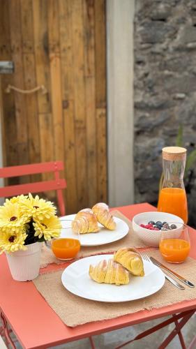 a red table with plates of food and orange juice at Old Aqueduct Village 1 - Guesthouse - Madeira in Serra de Água