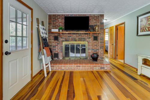 a living room with a brick fireplace with a tv at Sylva Riverfront Cabin Near WCU Pet-Friendly! in Sylva