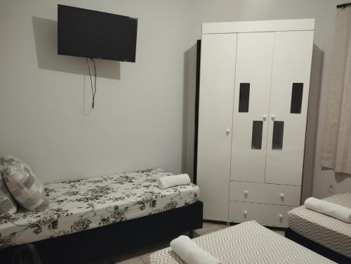 een slaapkamer met een bed, een kast en een tv bij Quarto Due na Sakura House in Indaiatuba