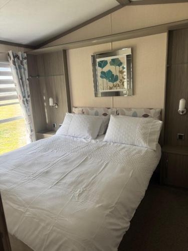 a large white bed in a room with a window at Spacious Modern Seaside Caravan in Lossiemouth
