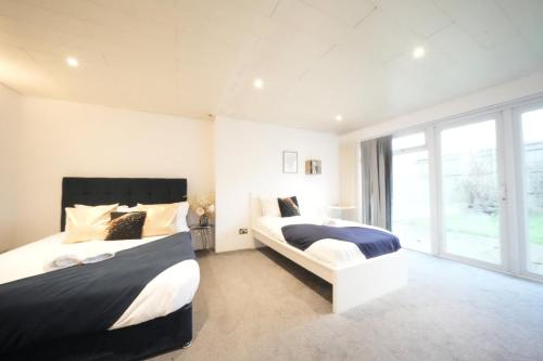 a bedroom with two beds and a large window at Airport Comfy Stay in Harmondsworth