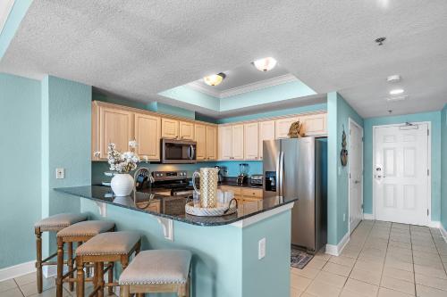 a kitchen with blue walls and a large island with bar stools at Crystal Shores West Unit 705 in Gulf Shores