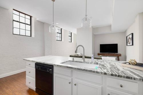 a kitchen with white cabinets and a sink and a tv at New Downtown JC Loft! in Johnson City