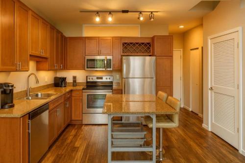 a kitchen with wooden cabinets and a stainless steel refrigerator at Penthouse Loft Forest Park View Free Parking in Tower Grove