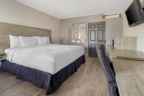 a bedroom with a large bed and a flat screen tv at Dannys Suites, SureStay Collection by Best Western in Beresford