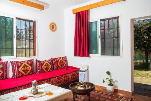 a living room with a red couch and windows at Paradise Farm 20 min from Rabat in Sale