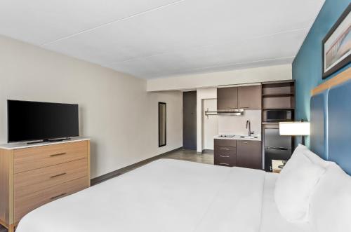 a hotel room with a large bed and a flat screen tv at Suburban Studios Charleston - Civic Center in Charleston