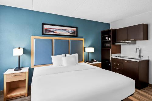 a bedroom with a large bed and a blue wall at Suburban Studios Charleston - Civic Center in Charleston