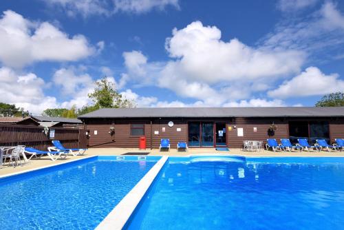 a swimming pool with chairs and a building at 10 Pinewood Retreat in Lyme Regis