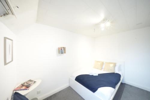 a small white bedroom with a bed and a table at Airport Comfy Stay in Harmondsworth