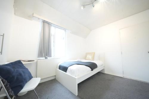 a white bedroom with a bed and a window at Airport Comfy Stay in Harmondsworth