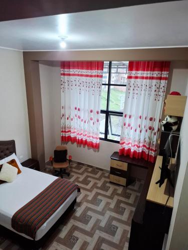 ein Schlafzimmer mit einem Bett und einem Fenster mit roten und weißen Vorhängen in der Unterkunft Departamento Platinum in Chota