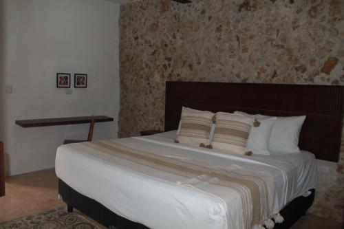 una camera da letto con un letto grande con lenzuola e cuscini bianchi di Casa Esquina Suite 1 a Mérida