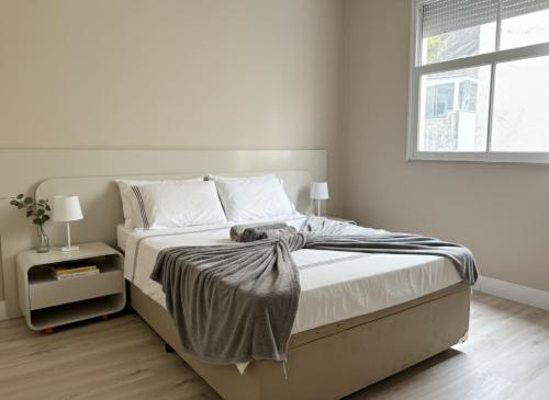 een witte slaapkamer met een bed en een raam bij Apartamento à Beira-Mar na Urca in Rio de Janeiro