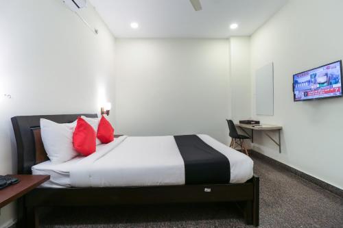 a hotel room with a bed with red pillows at Capital O GN Suites in Bengaluru