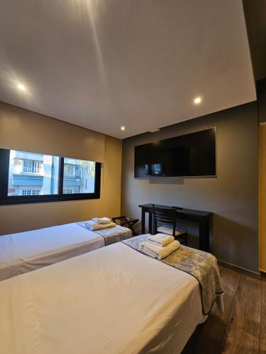 a bedroom with two beds and a flat screen tv at Hotel Grand Lago in Posadas