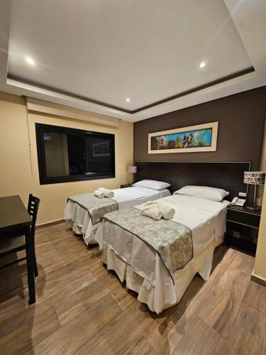 a hotel room with three beds and a flat screen tv at Hotel Grand Lago in Posadas