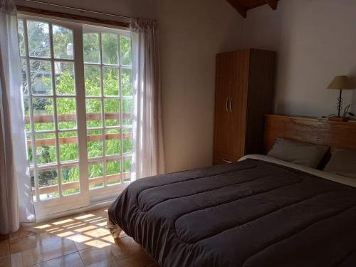 a bedroom with a bed and a large window at Casa en La Caleta Normandita in Mar de Cobo