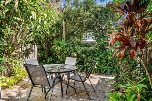 a glass table and chairs in a garden at Peaceful Garden Escape - 2BR Noosaville Getaway in Noosaville