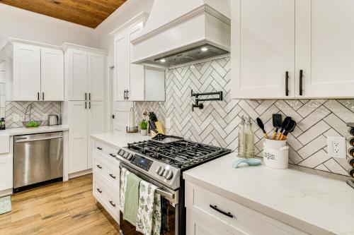 a kitchen with white cabinets and a stove top oven at 1 Mi to Dtwn Brenham! The Bell and Bloom Cottage in Brenham