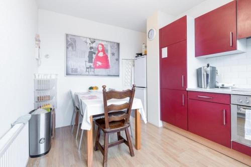 a kitchen with red cabinets and a table with a chair at Delightfull spacious room in gorgeous home in Amsterdam