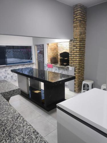 a kitchen with a black counter and a fireplace at Chácara Fim de Tarde in Barra do Garças