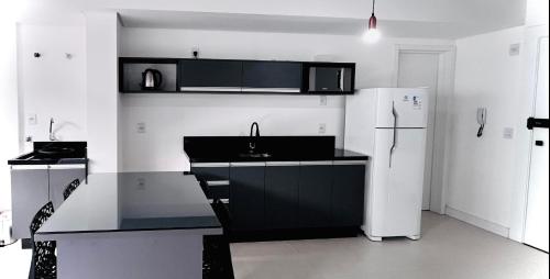 a kitchen with a sink and a refrigerator at Loft Blumenau in Blumenau