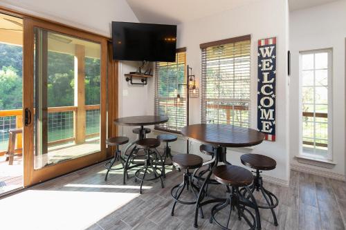 a kitchen with two tables and stools in a room with windows at Lazy Southern Getaway in Canyon Lake