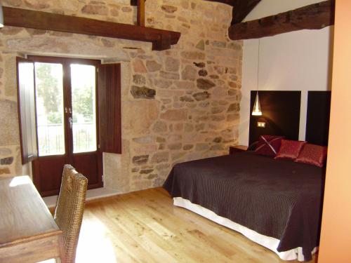 a bedroom with a bed and a stone wall at Bi Terra tu descanso zona Miraz Sobrado in Friol
