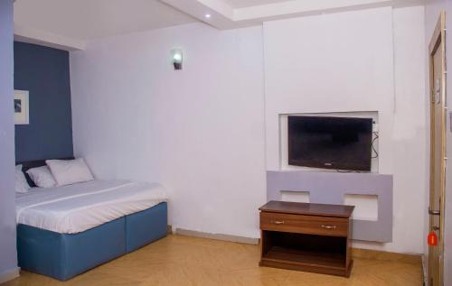 a bedroom with a bed and a tv on a wall at Morada Hotels Ltd in Lagos