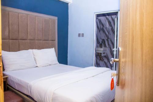 a bedroom with a white bed with a blue wall at Morada Hotels Ltd in Lagos