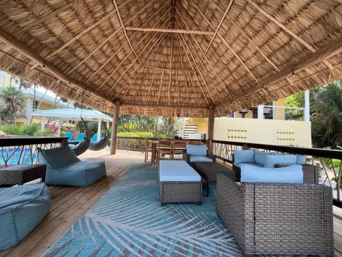 a patio with couches and chairs under a straw roof at Lucky Duck Villa - Private Beach Escape in Maya Beach