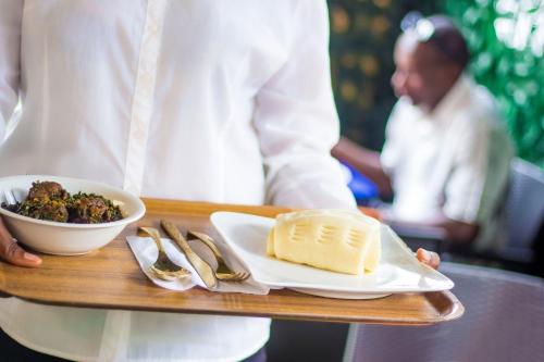 a person holding a tray with a plate of food at Morada Hotels Ltd in Lagos