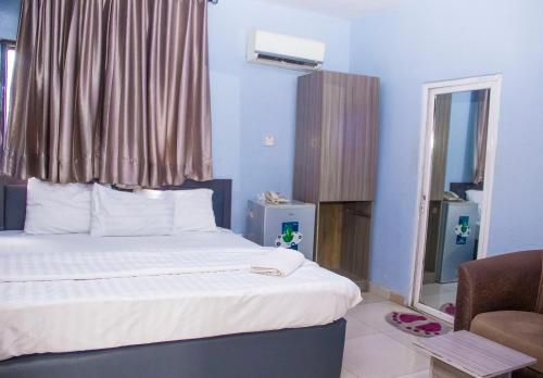 a bedroom with a bed with a window and a chair at Morada Hotels Ltd in Lagos