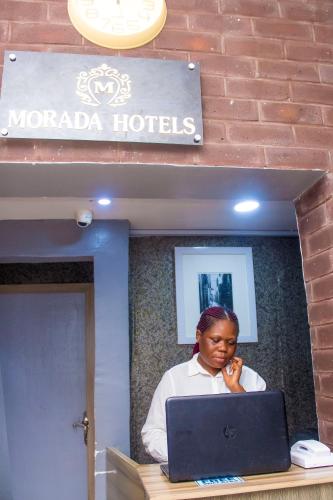 a woman sitting at a desk with a laptop at Morada Hotels Ltd in Lagos