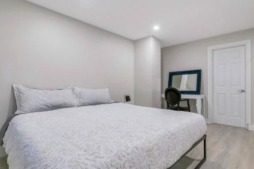 a white bedroom with a bed and a chair at Modern Spacious Ocean-view Suite with Private Ent in West Vancouver