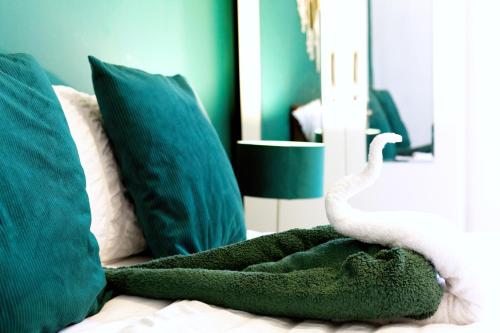 a bed with green pillows and a white towel at Beautiful 5Bedroom House - Contractors and Family near the Molineux stadium in Wolverhampton