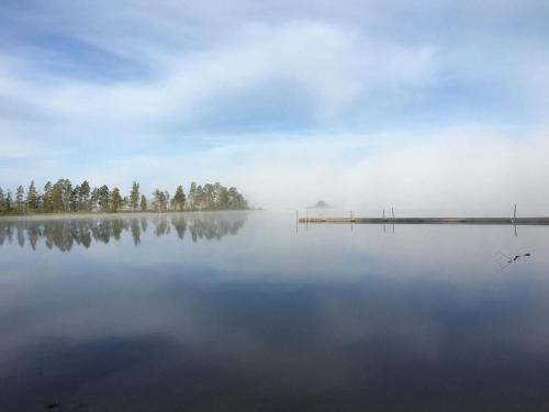 a misty lake with a dock and trees on the horizon at 6 person holiday home in Skibby-By Traum in Skibby