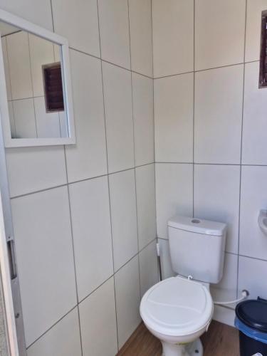 Un baño blanco con inodoro y espejo. en Daianne Silva Barbosa, en Belém