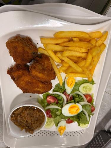 a plate with fried chicken and a salad with french fries at Chambres d'Hôtes Centre Ville in Dakar