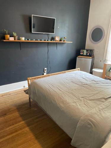 a bedroom with a bed and a tv on the wall at Ophelias Casa in Vancouver