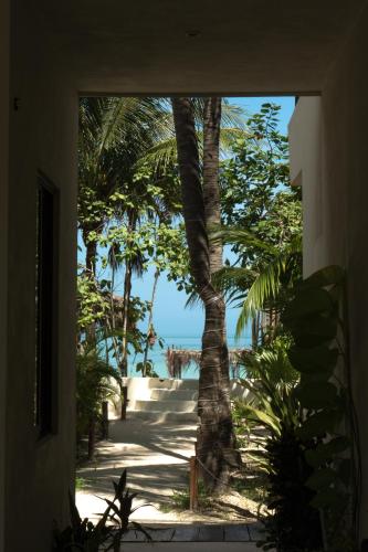 a view of the beach from a house with a palm tree at Hotel Boutique La Puerta Azul Beachfront - Adults Only in Holbox Island