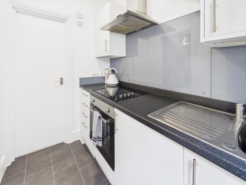 a kitchen with white cabinets and a sink at Stylish Maisonette with Hot Tub in Brighton & Hove