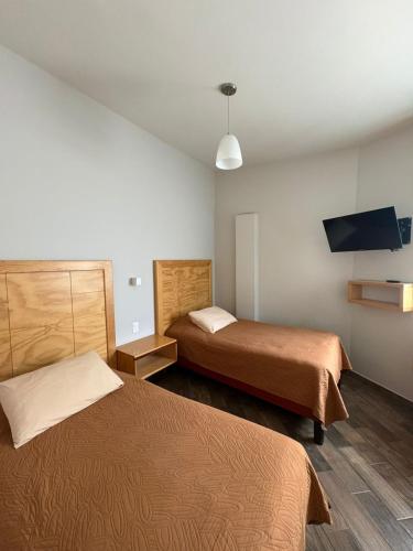 a hotel room with two beds and a flat screen tv at Privada 400 in Pachuca de Soto