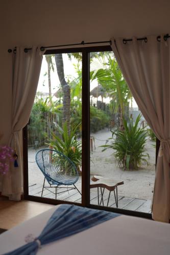 a room with a bed and a sliding glass door at Hotel Boutique La Puerta Azul Beachfront - Adults Only in Holbox Island