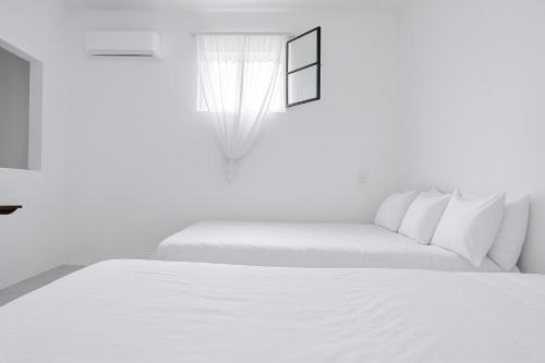 a white bedroom with two beds and a window at Departamento Puerto Vallarta in Puerto Vallarta